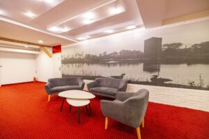 szare kanapy i fotel przy małym białym stoliku, w tle duży czarno-biały obraz