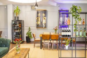 regał z winami, za nim duży stół z krzesłami, szable w szklanych szafkach na ścianie