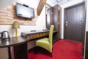 pokój hotelowy z biurkiem i zielonym fotelem