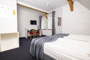 pokój z dwoma łóżkami pojedynczyni i biurkiem