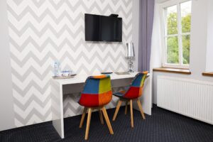 kolorowe krzesła przy białym biurku, telewizor nad nimi