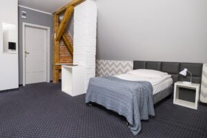 łóżko pojedyncze, po lewej stroni drzwi i komin